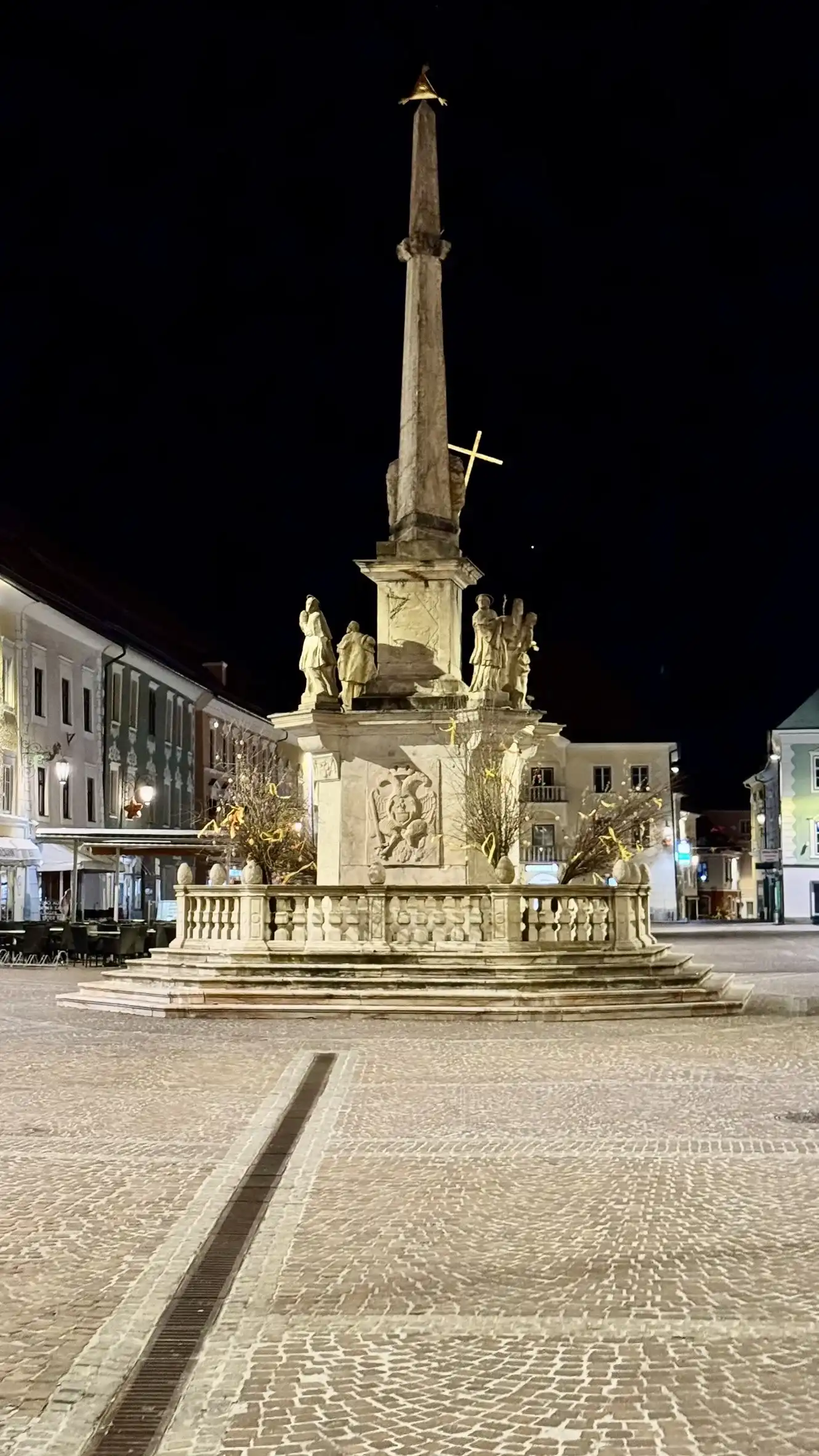 The "Plague Column" is at the centre of the main square. Night-time illumination.