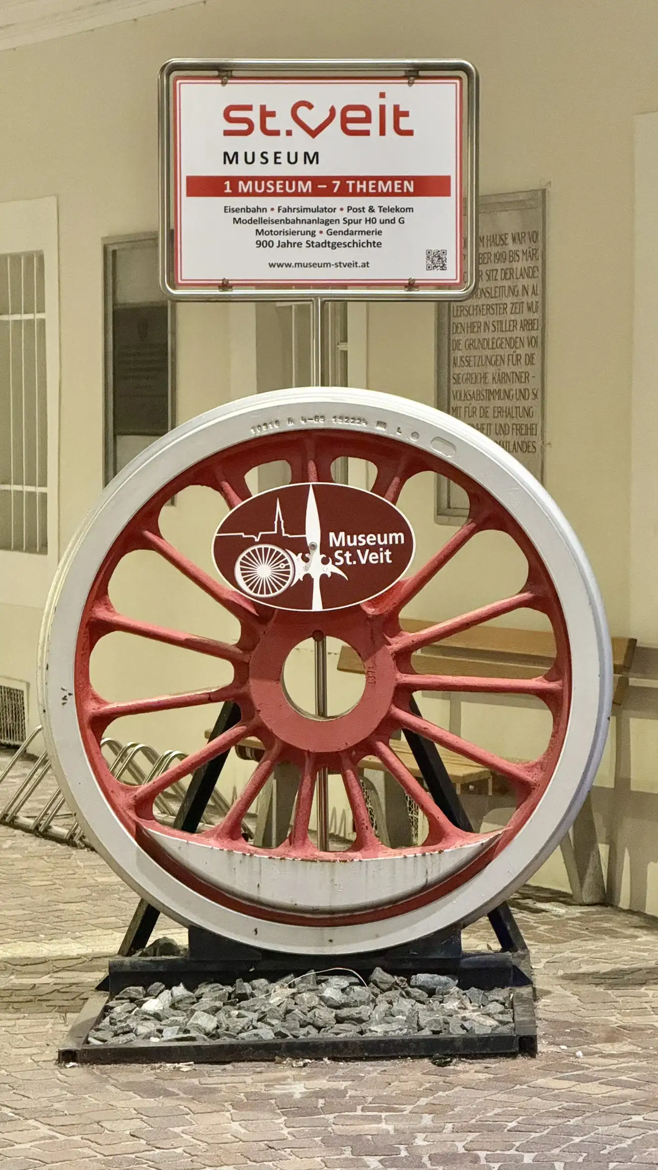 Informationstafel und Eisenbahnrad vor dem Museum