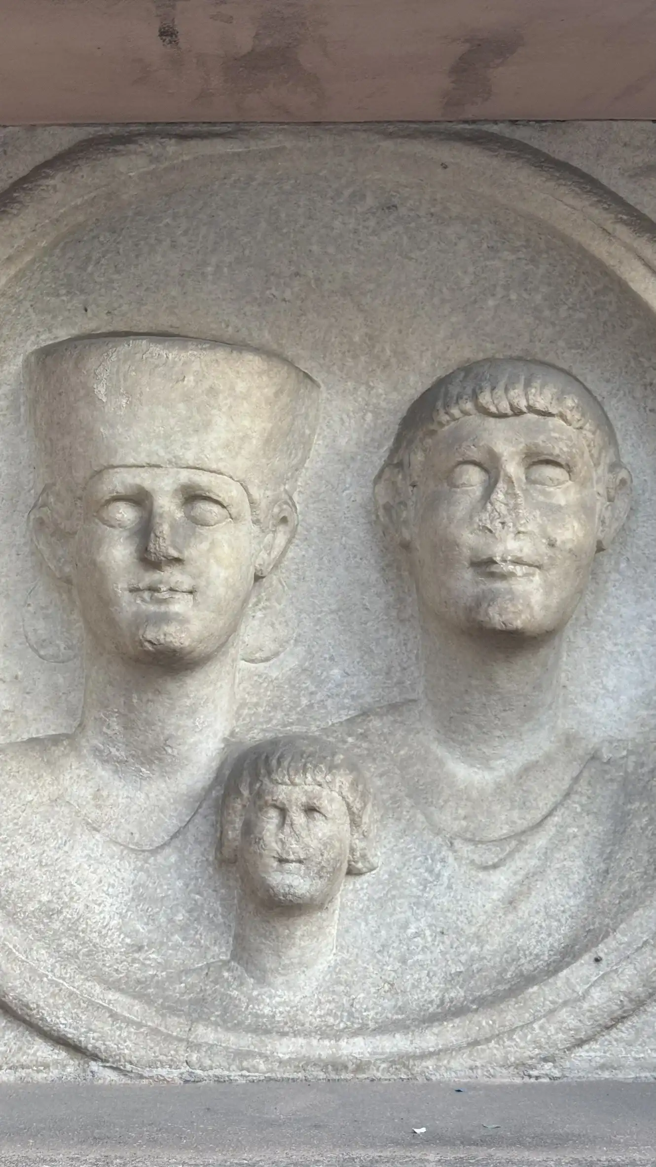 Circular medallion featuring the busts of a woman, a man, and a child