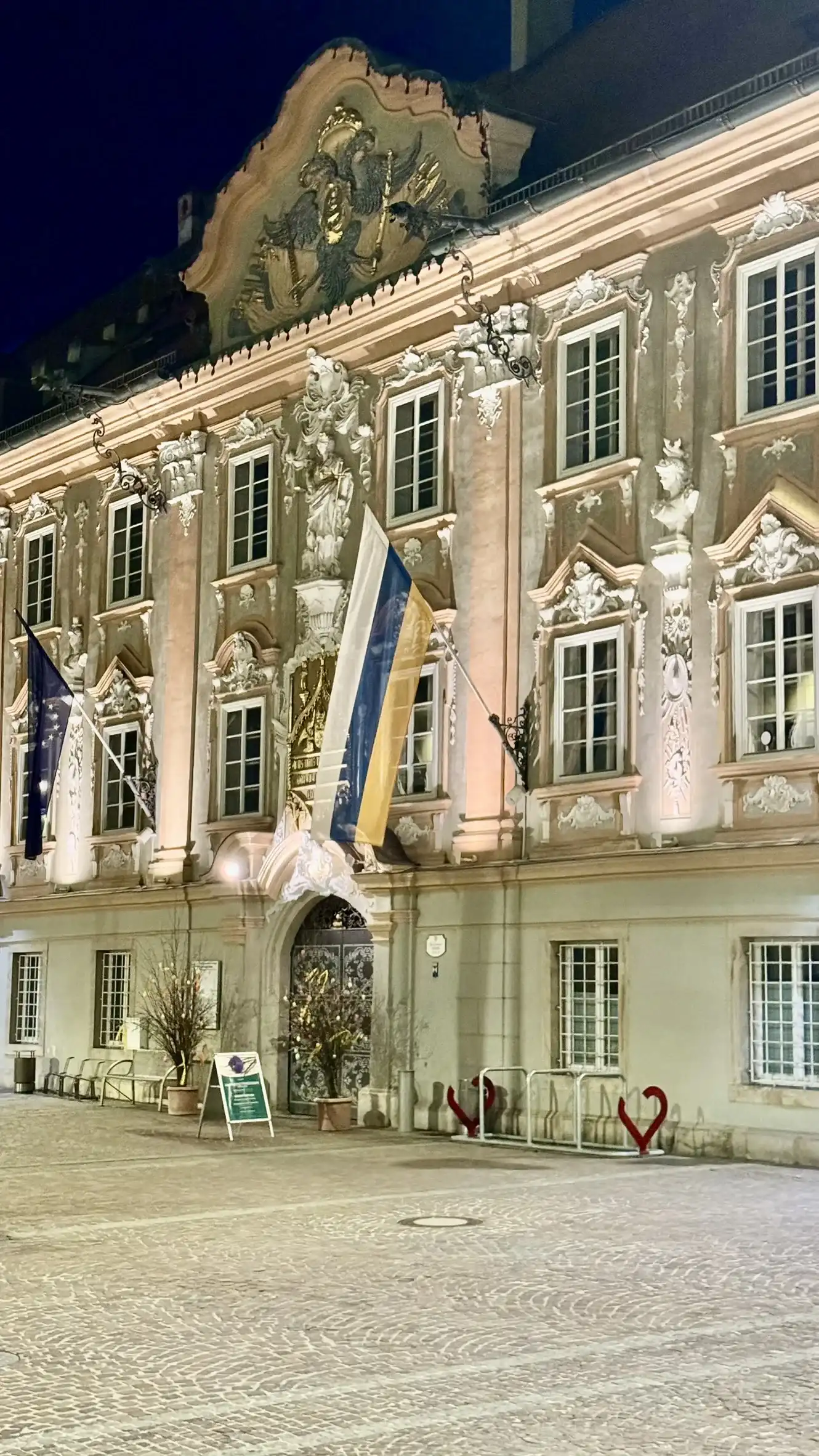 Rathaus im Norden des Platzes, bei Nacht beleuchtet.