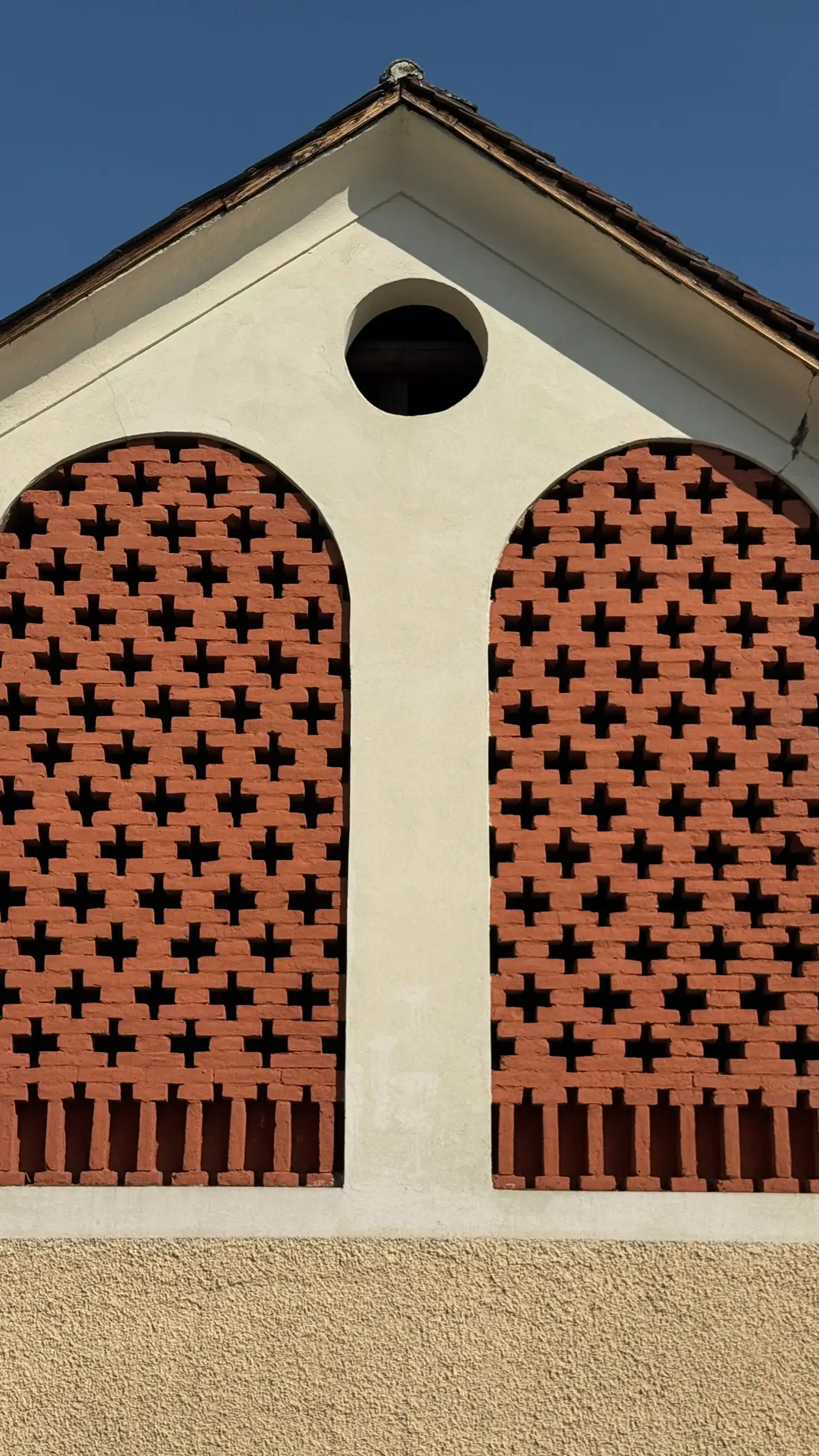 Two arched openings; brick latticework; circular vent