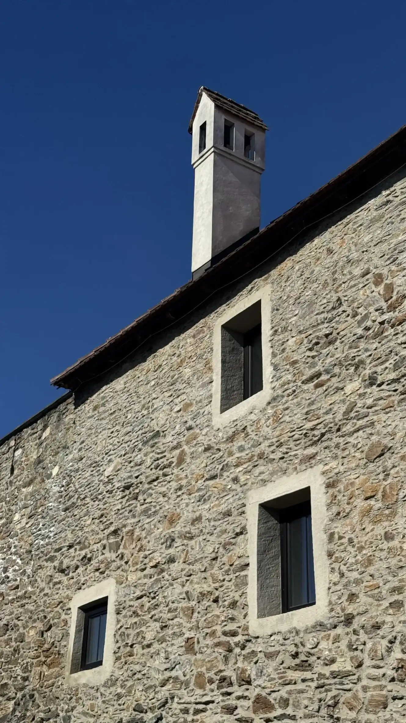 Rechteckige Fenster und Schornstein – moderne Ergänzungen der Mauer