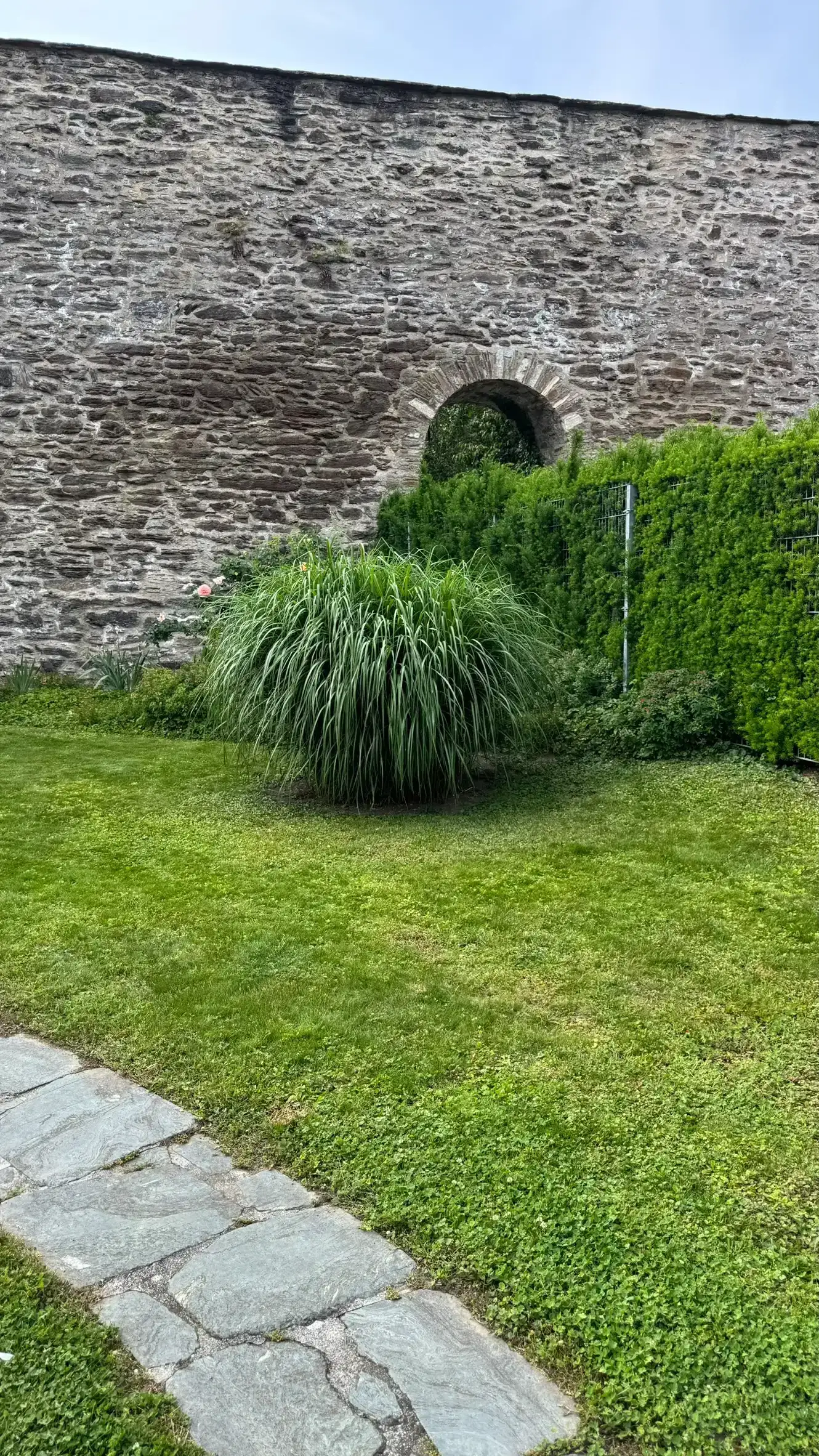 Foreground: curved path with irregular flagstones; background: NW town wall with arched opening