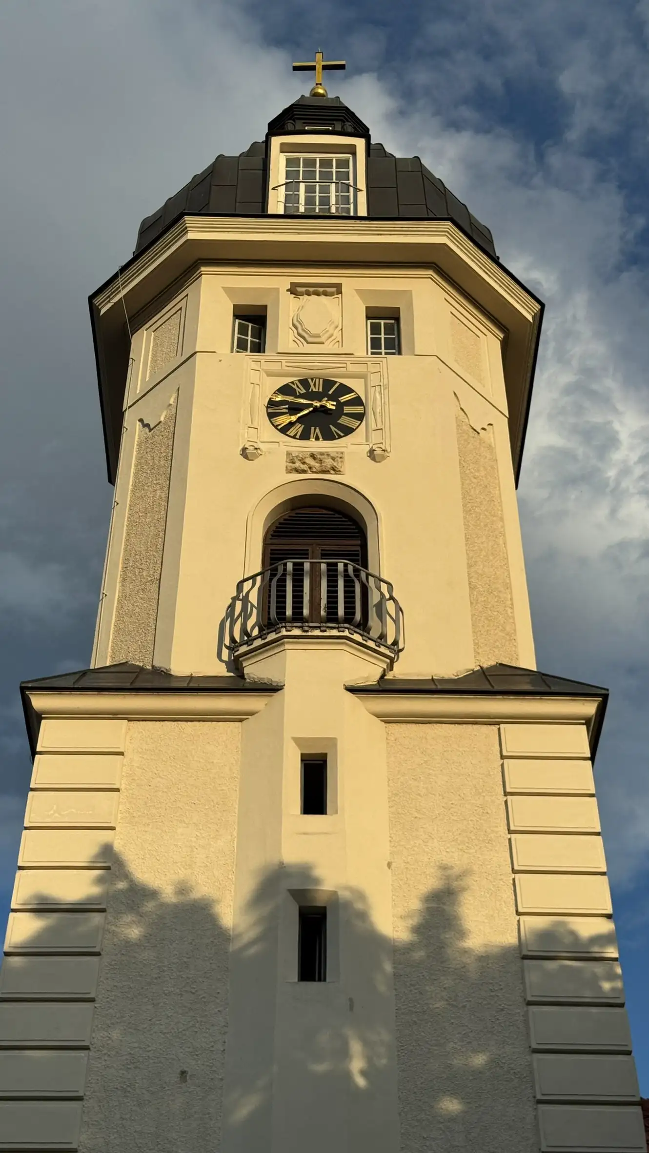 Church tower, NW face; mid-section with quoins; octagonal upper section with clock and semi-circular balustrade