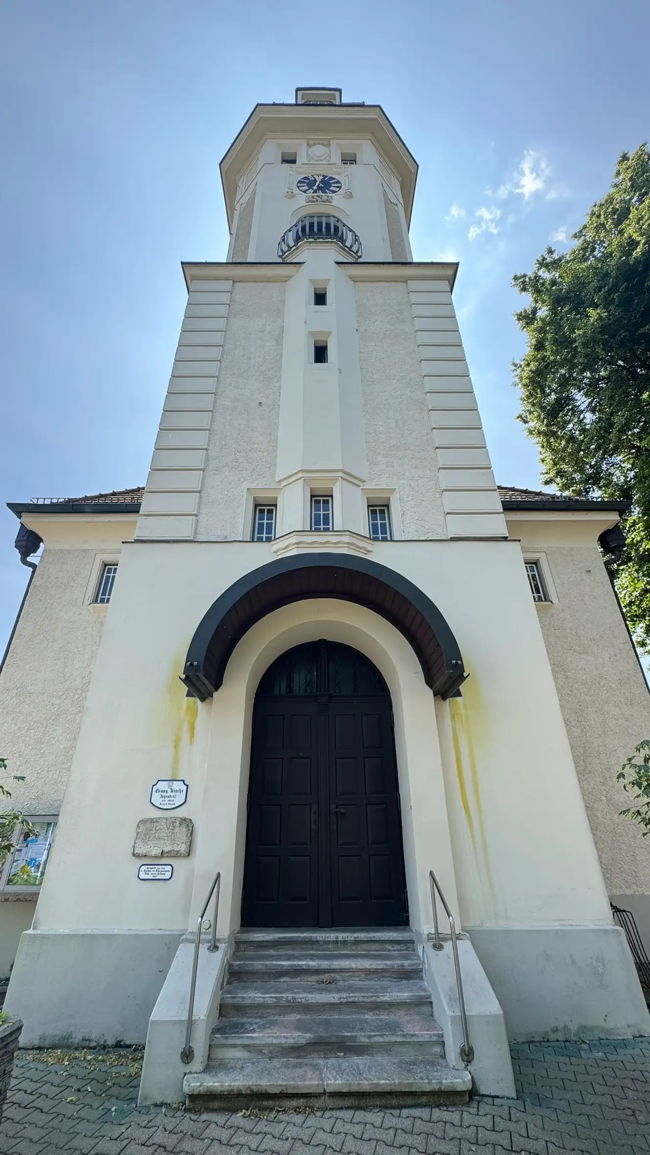 Westlicher Eingang mit Steinstufen, zweiflügeliger Holztür und rundbogigem Vordach