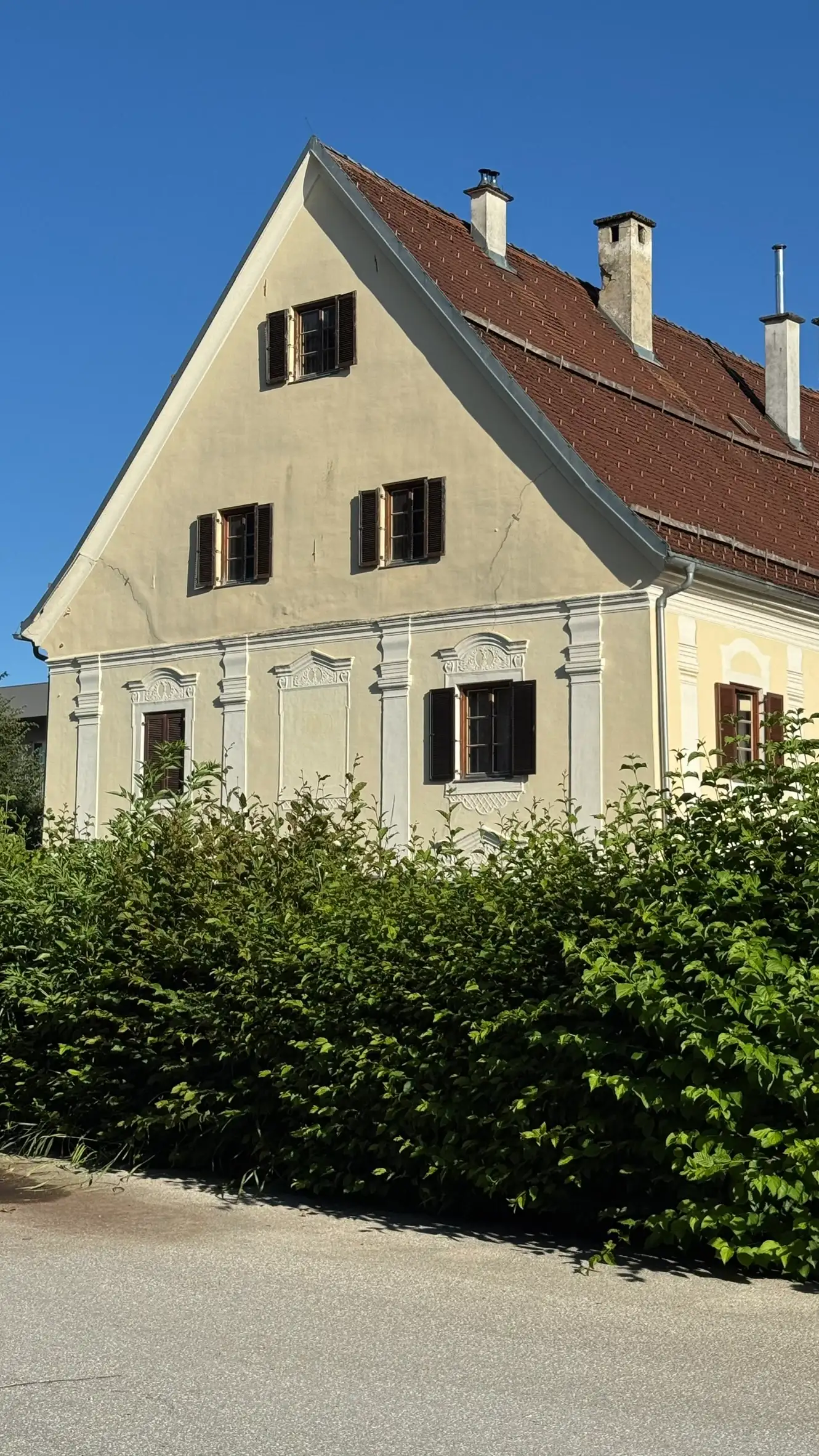 Two-storey Baroque building with a double-pitched roof; gable with three windows; four pilasters articulating the facade in view