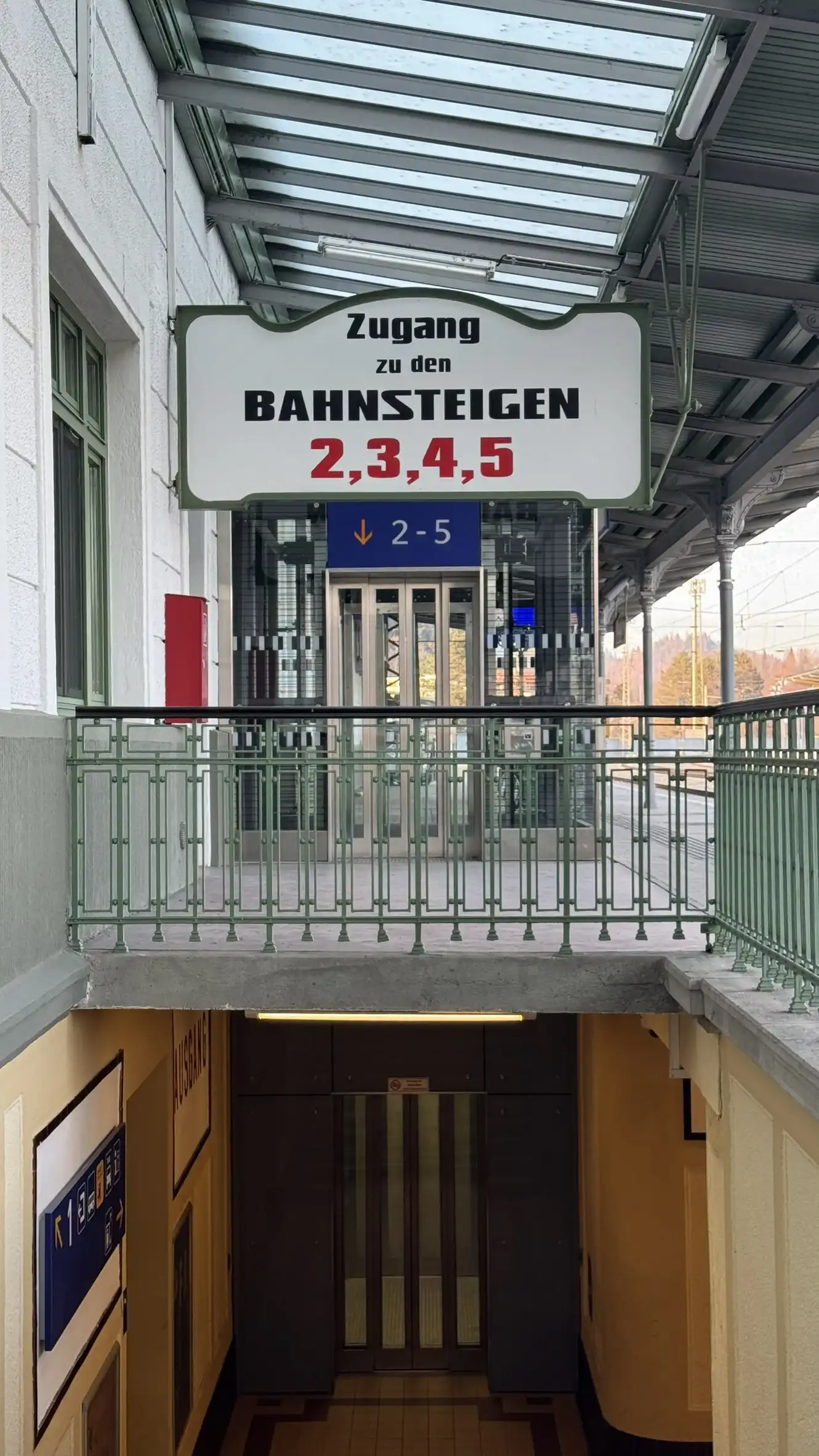 Bahnsteig-Leitschild mit lindgrünem Metallgeländer