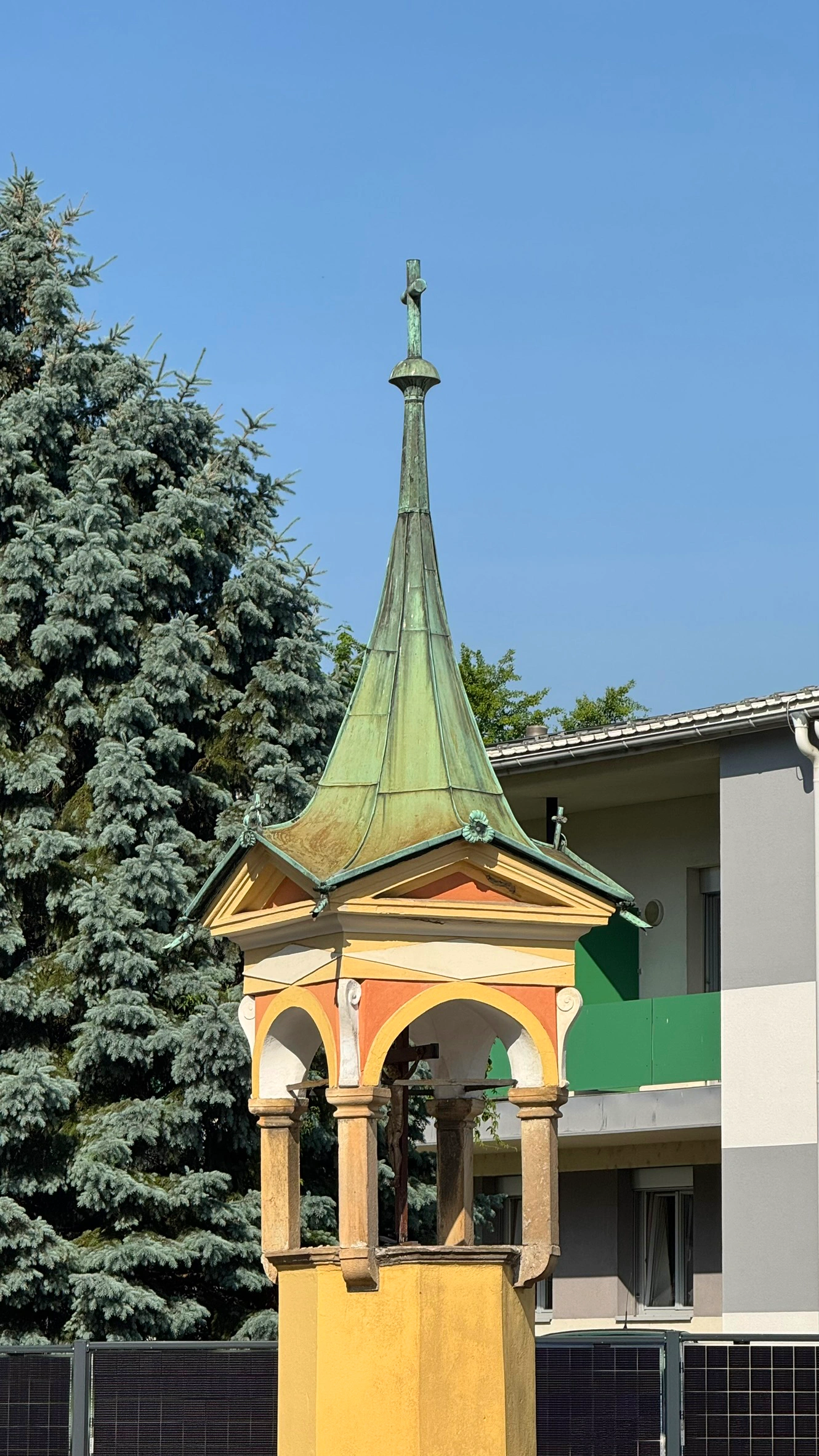 Achteckiger Sockel, Kruzifix in baldachinartiger Struktur, vier Giebel, Metalldach, Spitze mit Kreuz