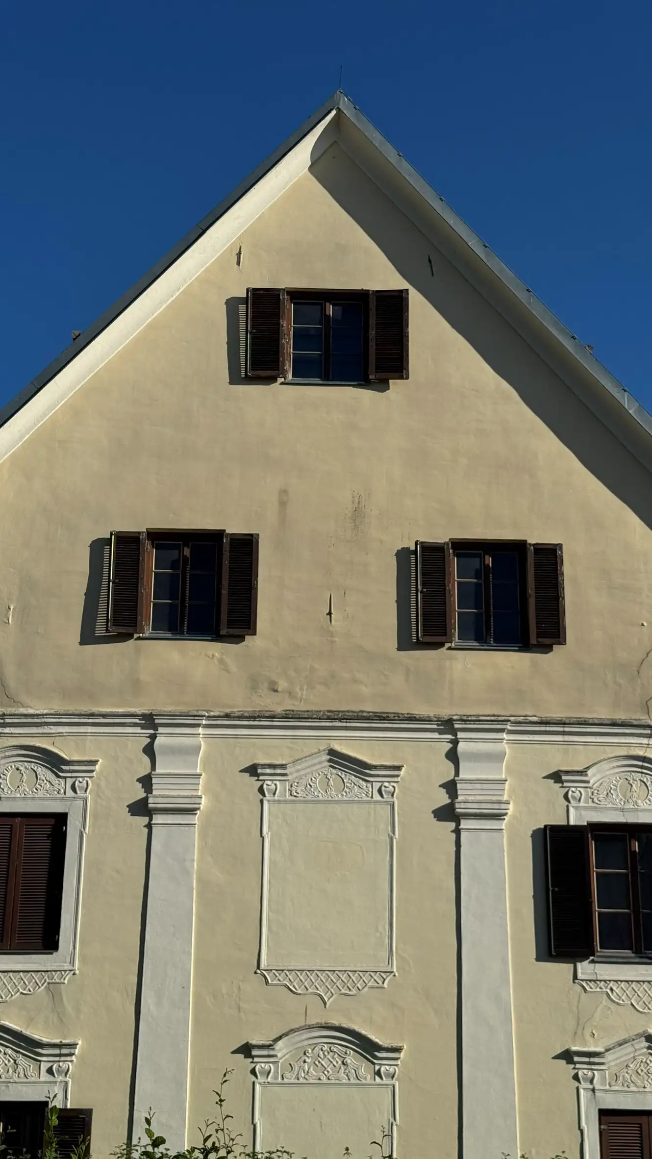 Gable with three windows; two pilasters in view; central blind windows framed by decorative moulding