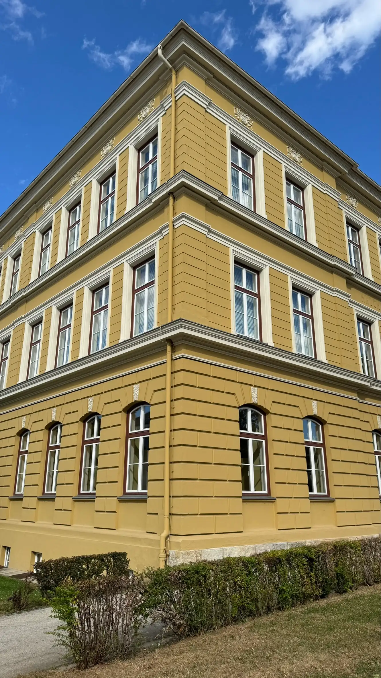 The three-storey building is painted in warm yellow, typical of Austro-Hungarian civic architecture.