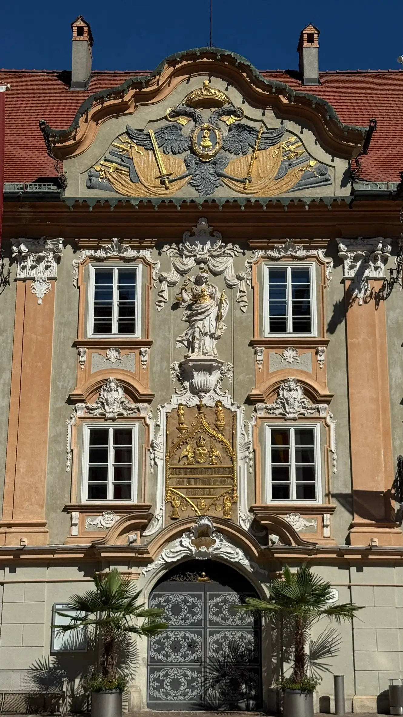 Mittelteil der Fassade (von oben nach unten): geschwungener Barockgiebel, Justitiafigur, Gussplatte, Rundbogenportal