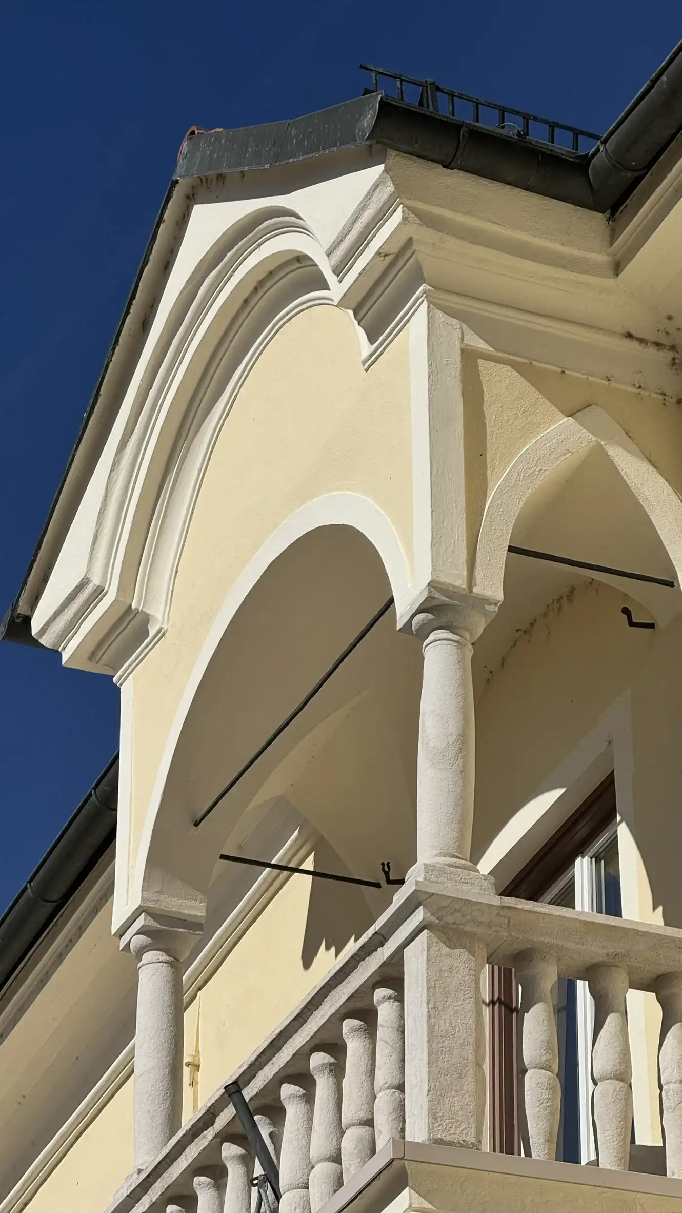 Top-floor balcony with canopy, three arches supported by two stone columns
