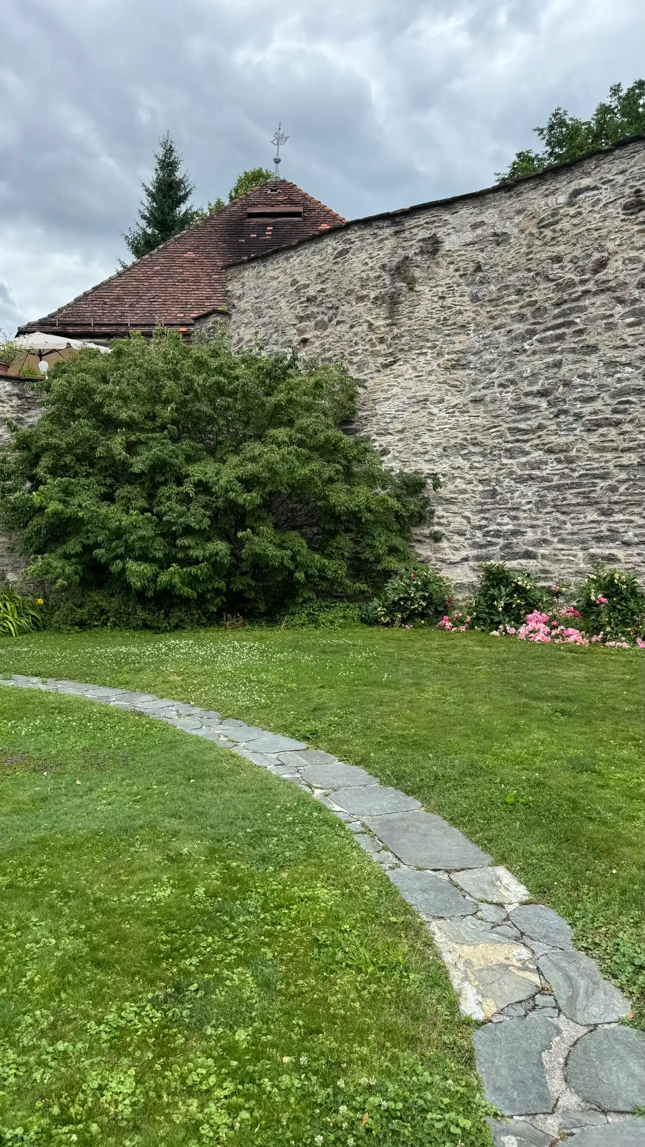 Vordergrund: geschwungener Weg aus unregelmäßigen Natursteinplatten; Hintergrund: Bastionsturm und NW Stadtmauer.