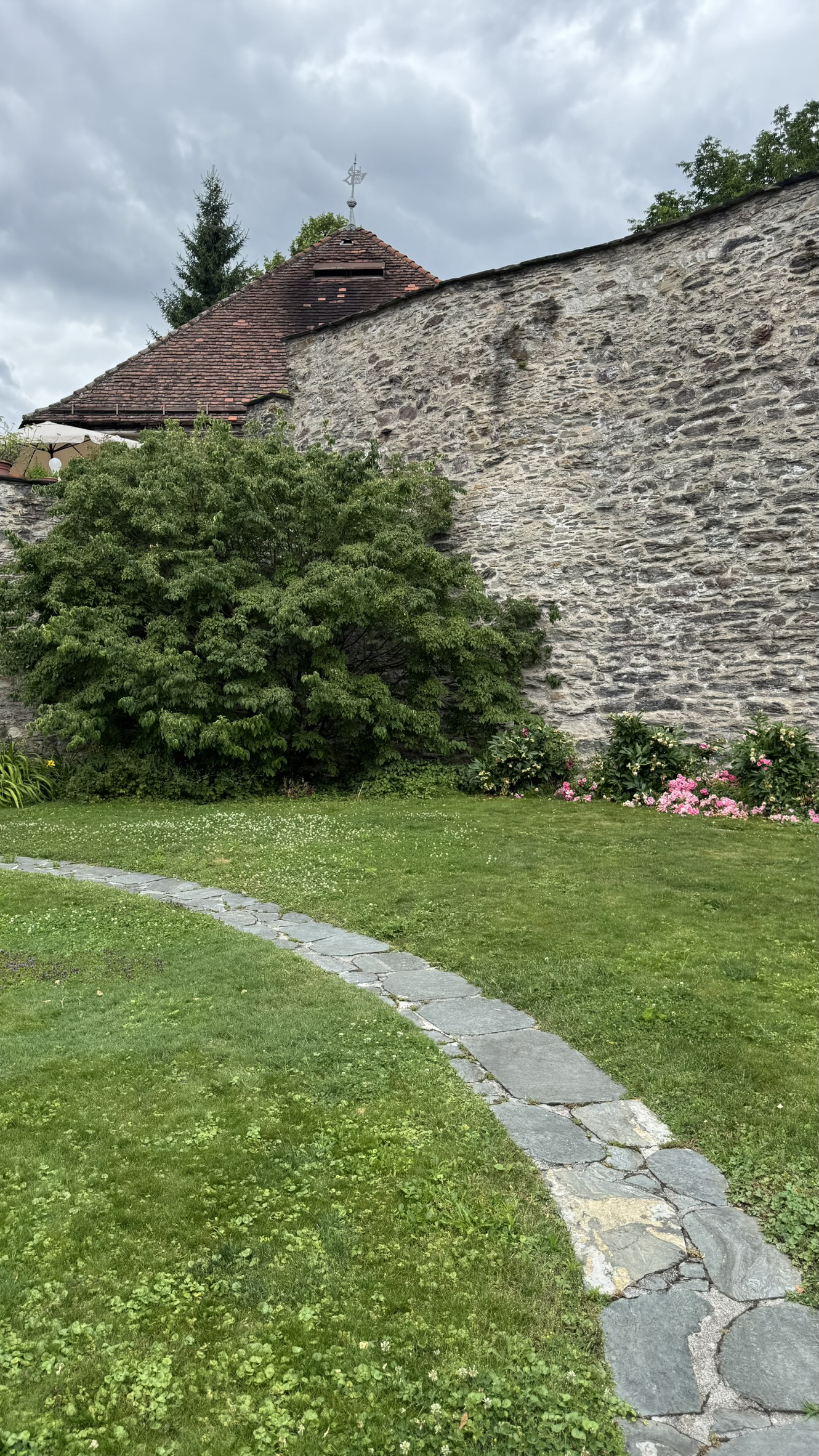 Foreground: curved path paved with irregular flagstones; background: bastion tower and NW town wall