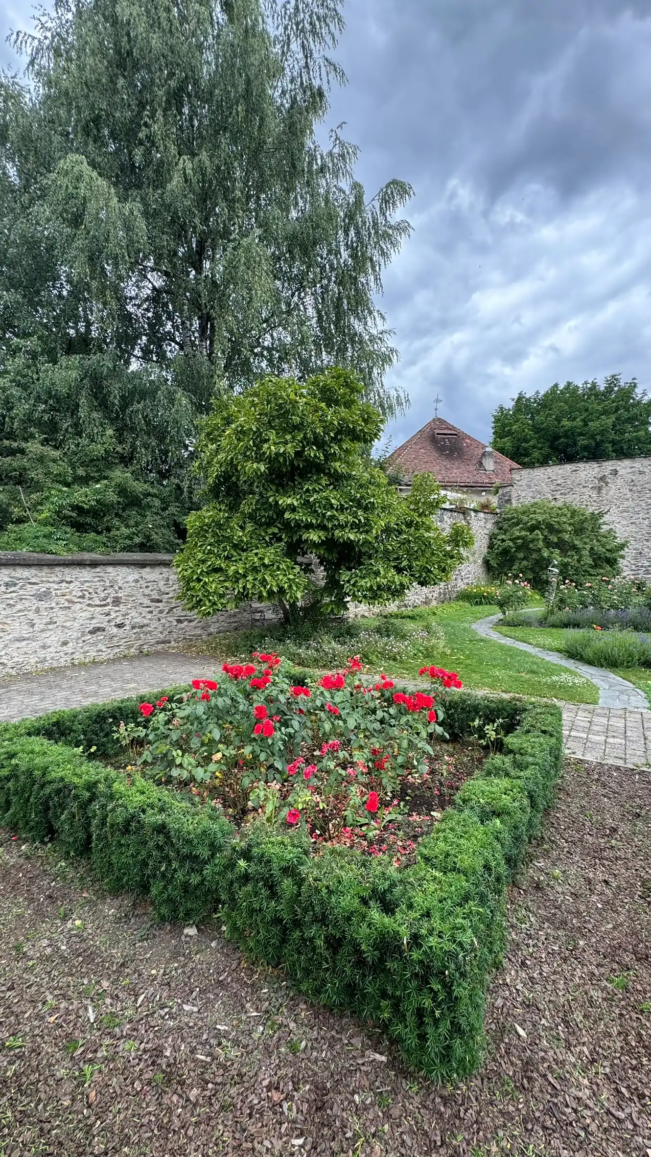 Blumenbeet, eingefasst von einer niedrigen, rechteckigen Schnitthecke; Bastionsturm im Hintergrund.