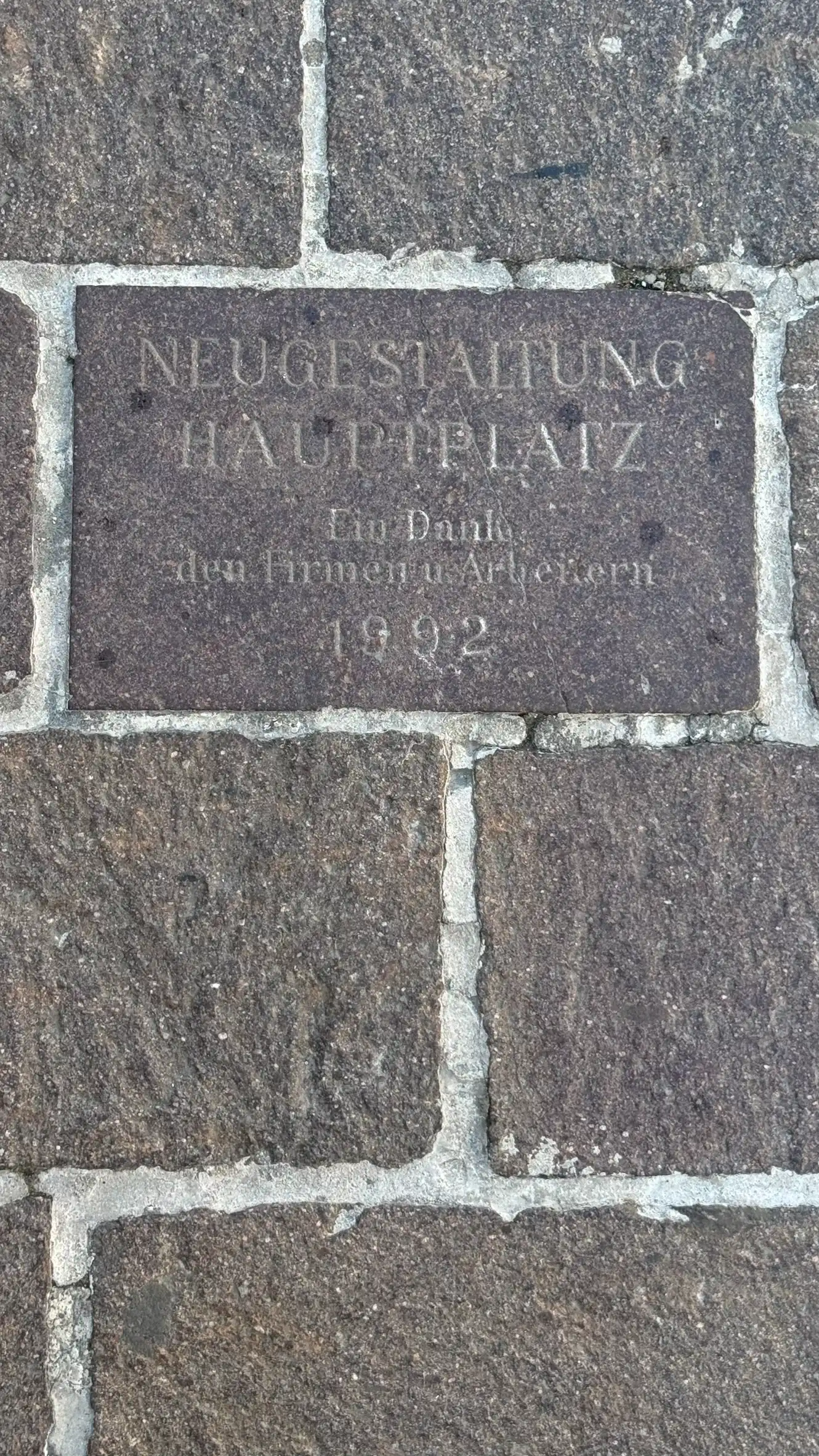 Eine gravierte Bodenplatte (dat. 1992) erinnert an die Neugestaltung des Hauptplatzes.