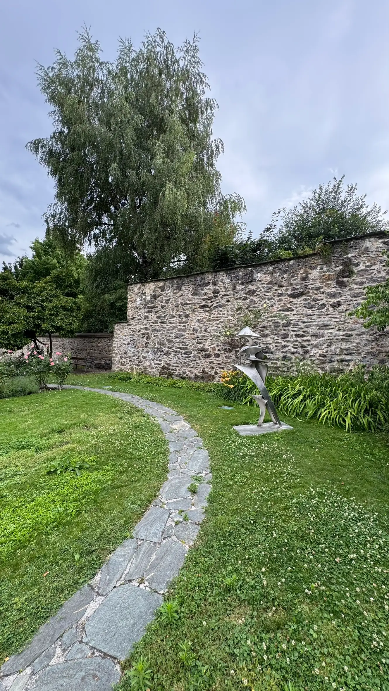 Foreground: curved path paved with irregular flagstones; background: SW town wall