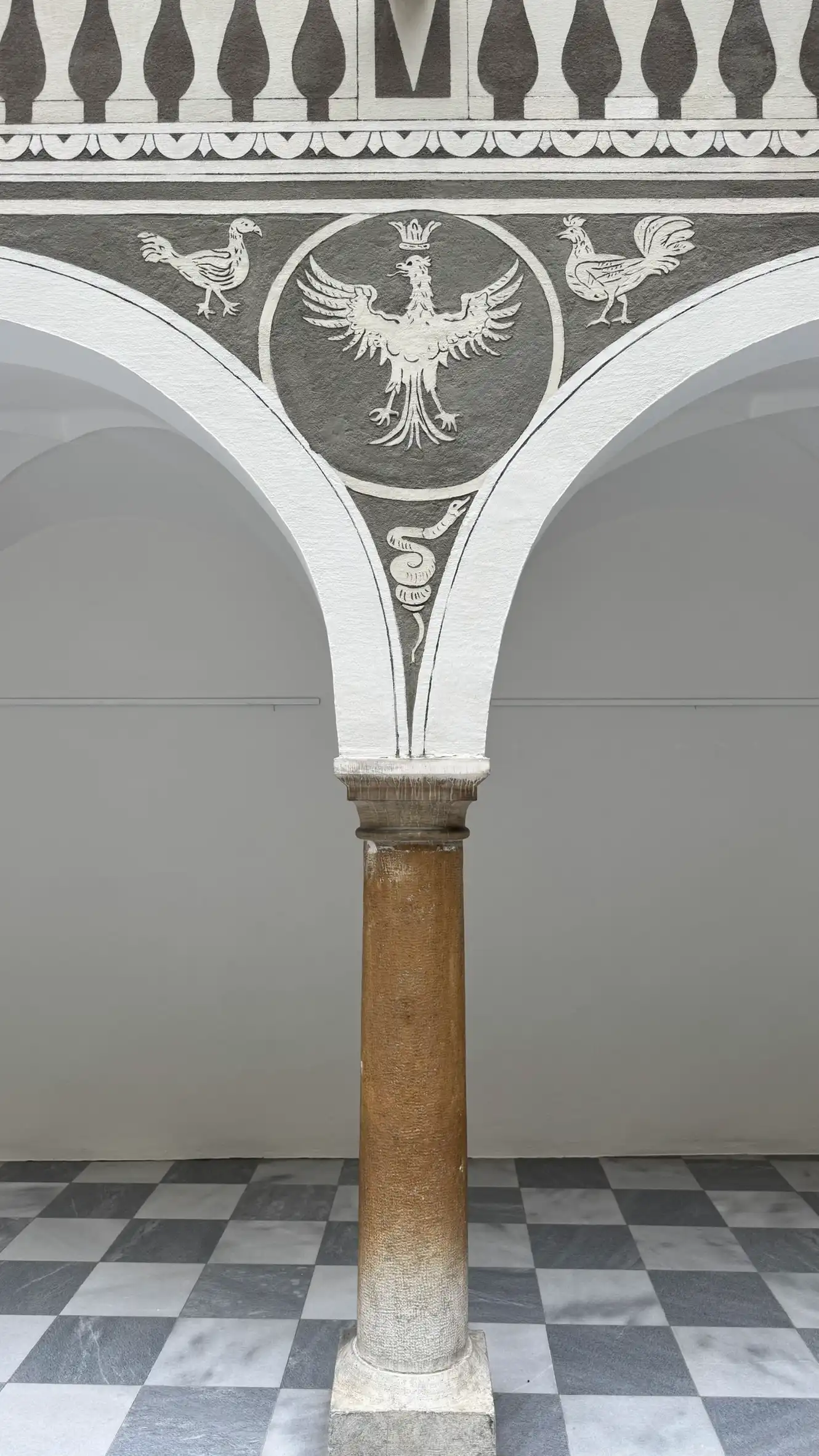 Eine Steinsäule trägt den Spandrel zwischen zwei Bögen sowie die darüber liegende Balustrade.