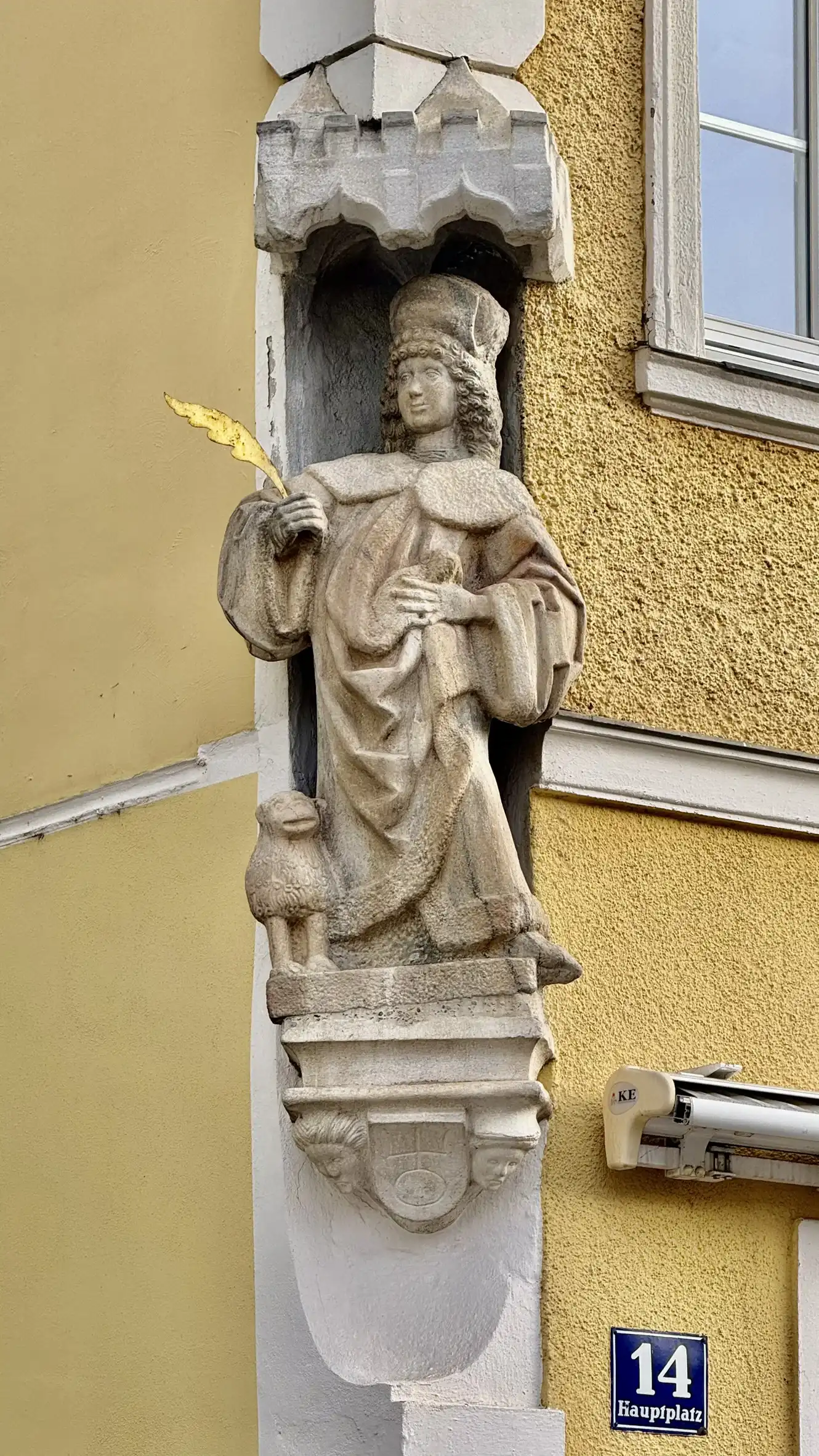 Eine Steinfigur des heiligen Veit ist in einer überdachten Ecknische angebracht.