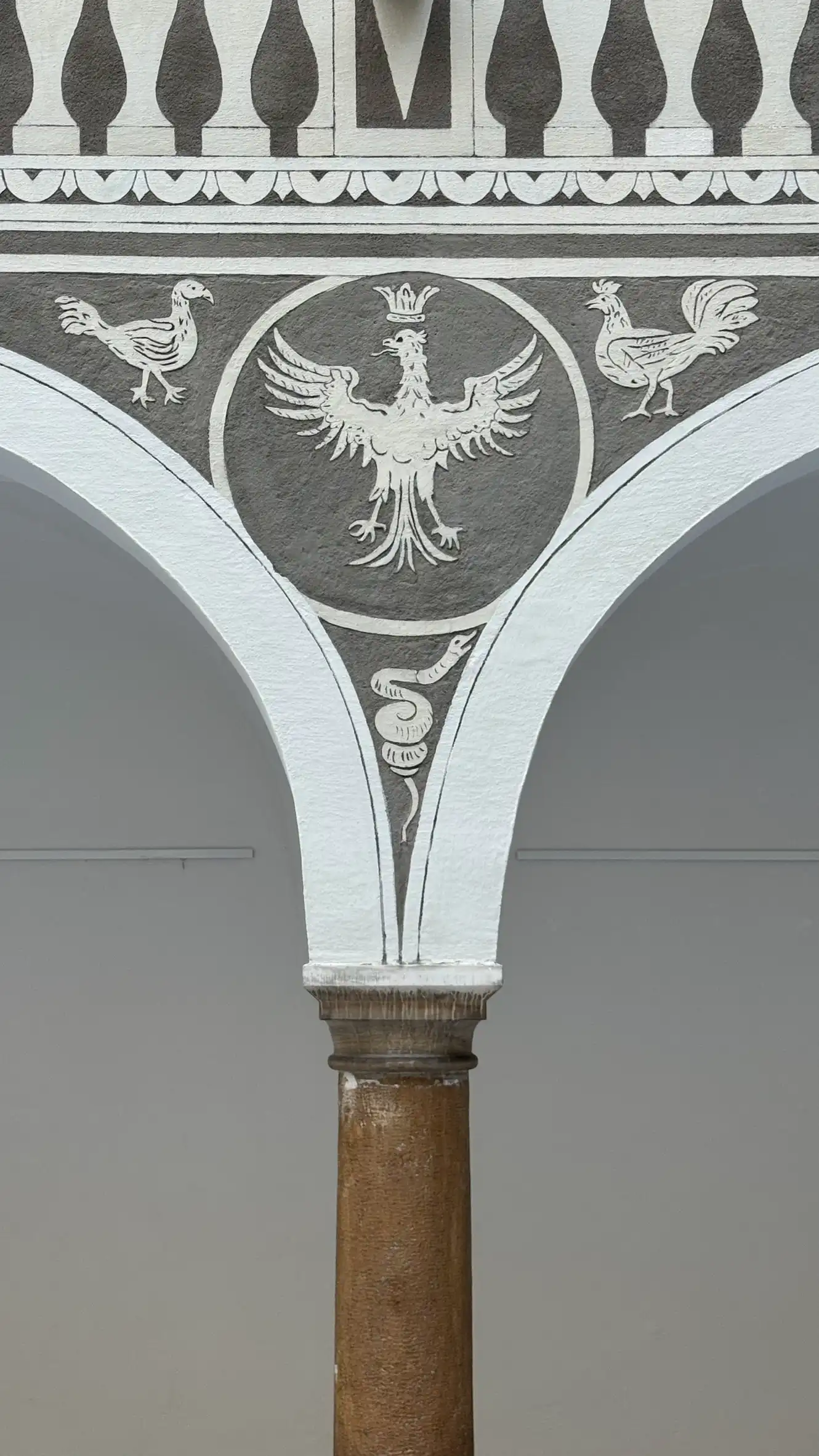 Dekoratives Sgraffito mit einem gekrönten Adler und einer sich windenden Schlange schmückt den Zwickel.