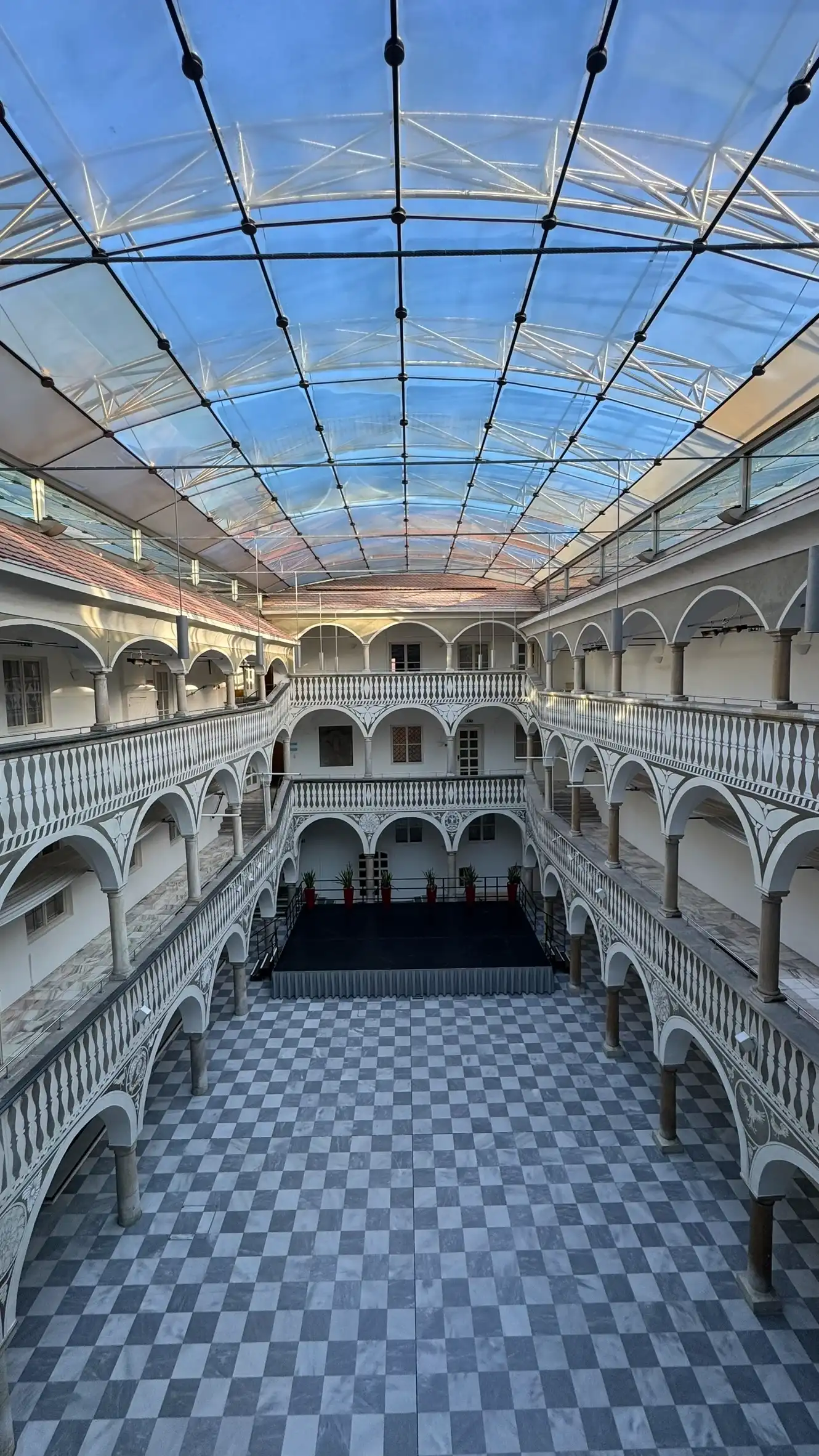 The arcaded courtyard is enclosed by a modern glass-and-steel roof.