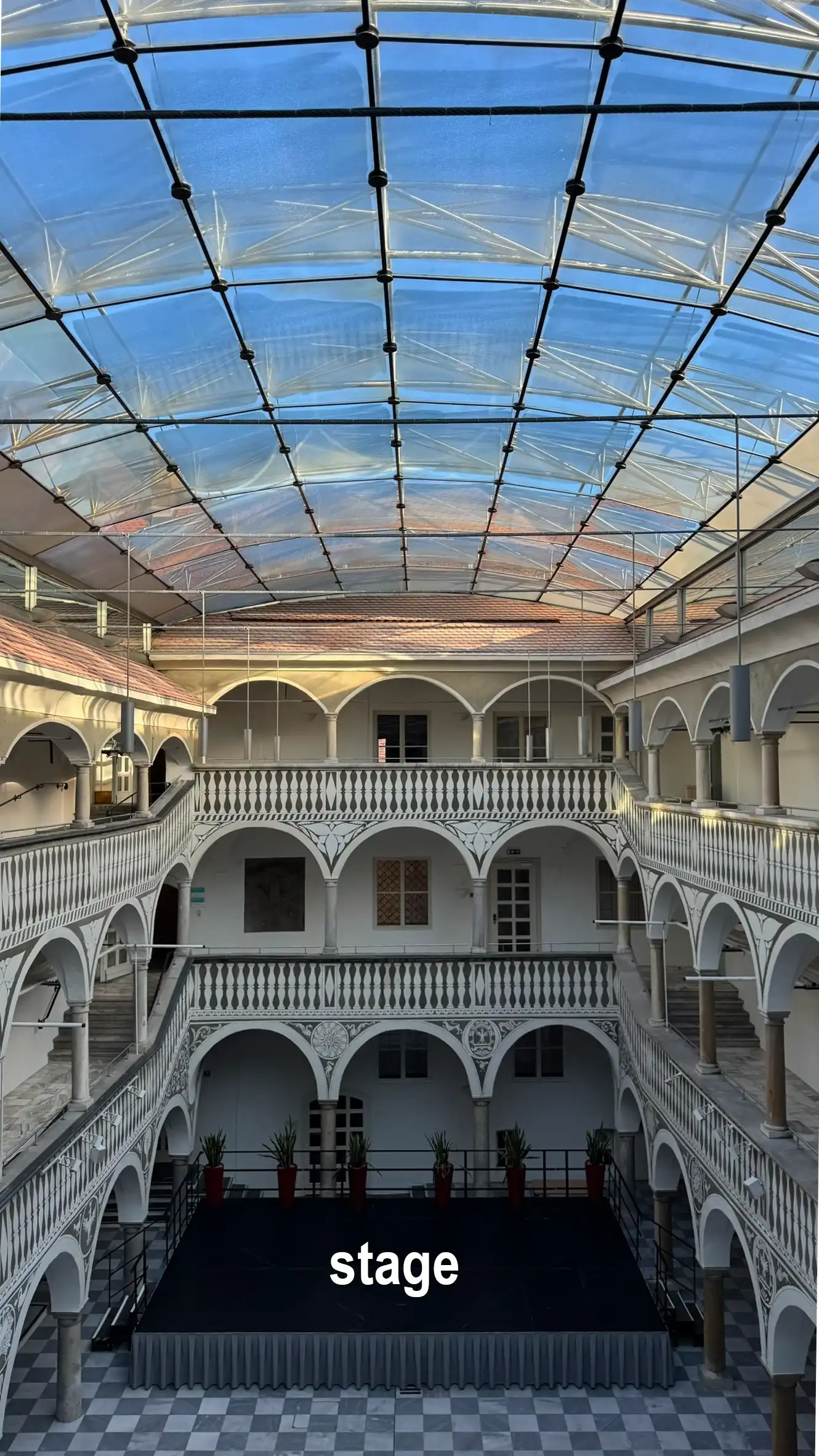 The ground floor stage highlights the courtyard’s function as an event venue.