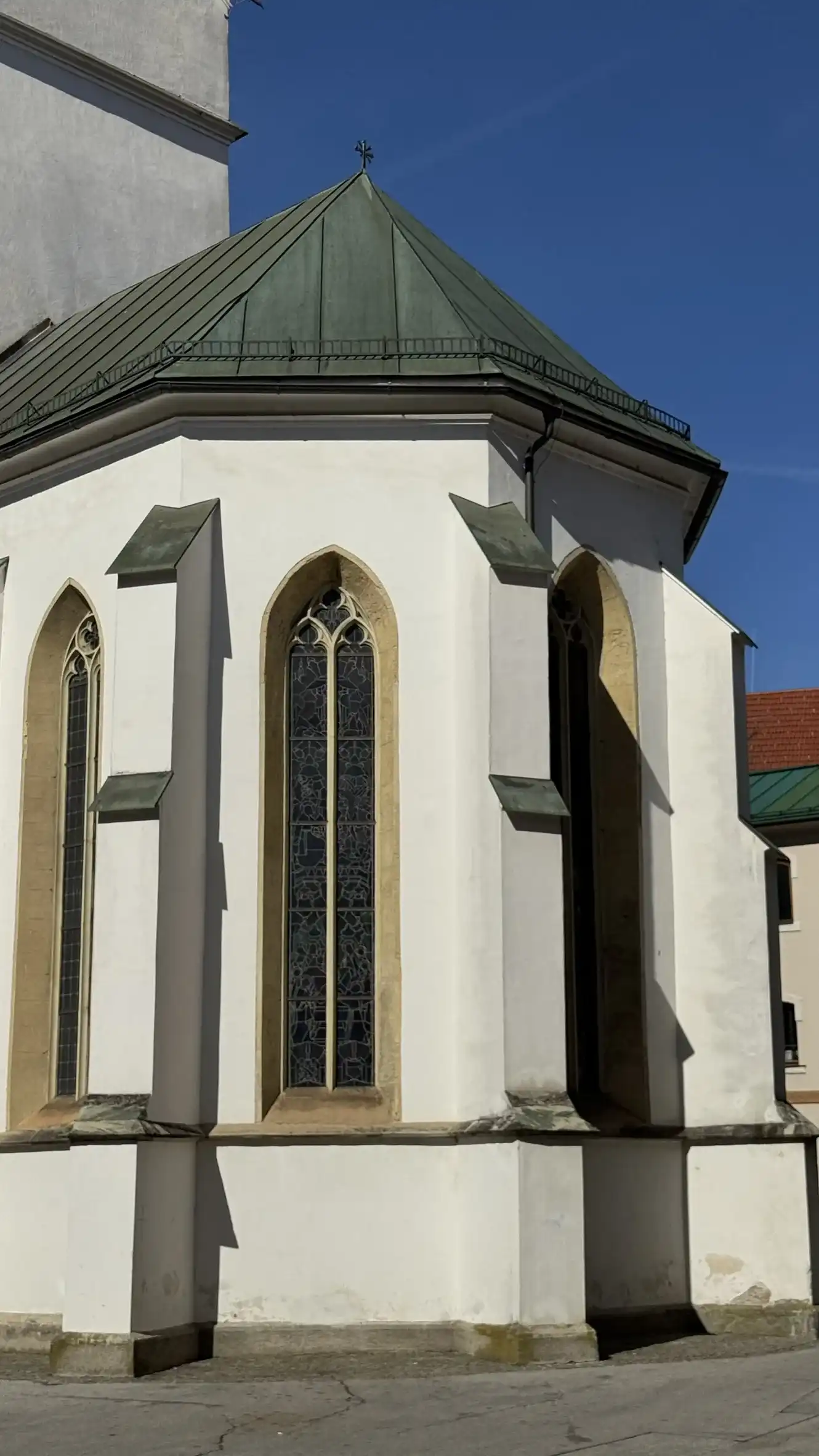 Polygonale Apsis nach Osten gerichtet; gotische Fenster und dreifach gestufte Strebepfeiler