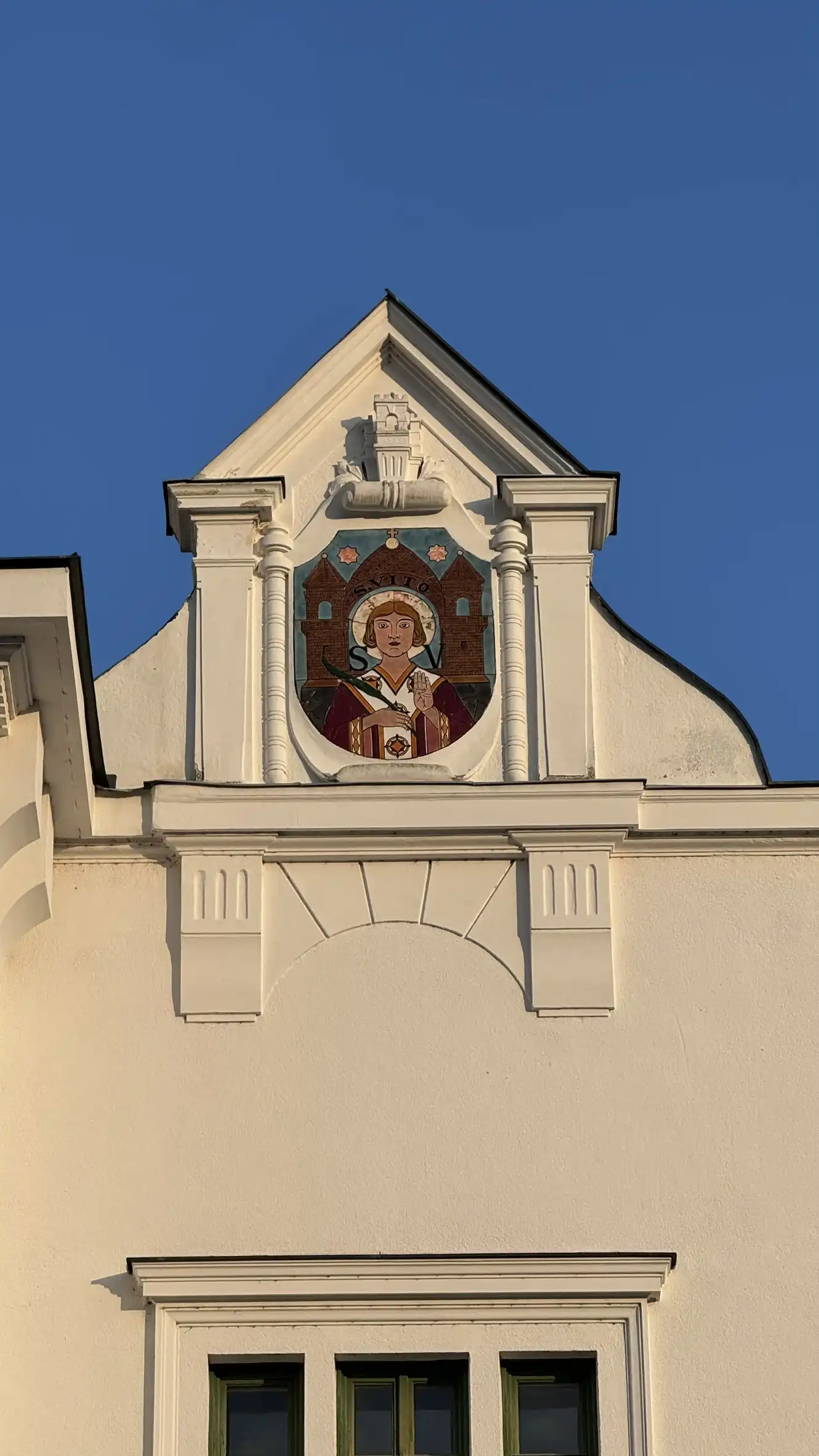 Dreiecksgiebel mit zwei Stützpfeilern, geschwungenen Giebelflügeln und zentralem Wandgemälde